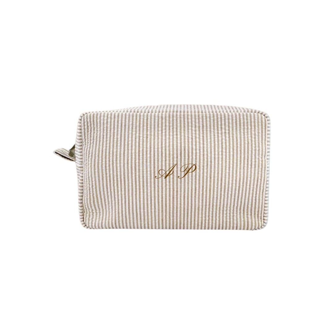 Beige striped pouch with gold monogram on a white background